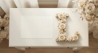 Elegant cream letter L decorated with delicate roses on white envelope, romantic floral monogram design for wedding invitations and luxury stationery.