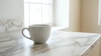 White ceramic coffee cup on marble kitchen counter with natural window light creating peaceful morning atmosphere for home decor and lifestyle concepts.