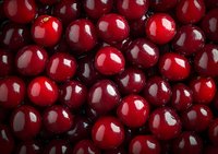 Fresh ripe red cherries background with glossy surface and natural shadows, macro food photography showing juicy fruit texture and vibrant color.