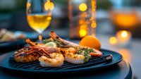 Grilled jumbo shrimp and prawns served on black plate with herbs and citrus garnish, romantic dinner setting with wine glass and warm bokeh lights in background.