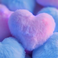Soft pink heart-shaped plush cushion on blue fluffy background with dreamy pastel colors and gentle bokeh effect, creating romantic and tender mood for valentines designs.