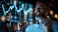 Successful mature businessman celebrating victory near digital charts. Emotional male executive enjoying achievement in modern office with blue data visualization.