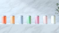 Colorful aluminum beverage cans in pastel and metallic colors arranged in row on white marble surface with minimal plant decoration. Modern drink packaging mockup.