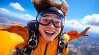 Young woman skydiver in orange jumpsuit and goggles smiling during freefall with landscape below. Extreme sports adventure and adrenaline rush concept.