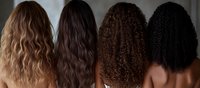 Back view of four women showing different natural hair textures and colors from blonde to black, representing hair care and beauty diversity.