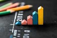 Colorful wooden blocks arranged as ascending bar graph on black chalkboard background showing growth trend and business progress concept.