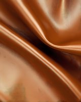 Smooth flowing brown satin fabric with gentle folds and creases creates elegant waves and soft shadows, suitable for luxury fashion and textile backgrounds.