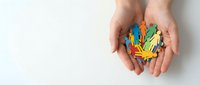 Hands holding colorful paper cutout figures representing diversity, teamwork and inclusion concepts for community outreach and social unity campaigns.