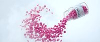 Pink capsules spilling from glass bottle on white background. Medical supplements, vitamins, pills scattered in dynamic motion for healthcare design.