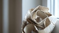 Crumpled brown paper bag in hands ready for recycling waste management and environmental sustainability concept in modern home interior.