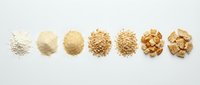 Progression of ground grain flour stages from fine powder to coarse meal and crushed cereal grains on white background for food processing and baking.