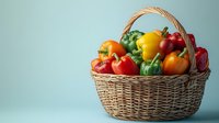 Fresh colorful bell peppers in wicker basket against blue background, organic vegetables for healthy eating and cooking. Suitable for food blogs and recipes.