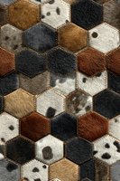 Luxurious cowhide hexagonal patchwork pattern with natural fur textures in brown, black, white and gray tones for interior design and upholstery projects.