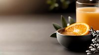 Fresh orange slice in black bowl with juice glass, green leaves and white flowers on neutral surface for beverage and wellness content.