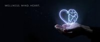 Hand holding glowing heart and brain symbol representing wellness, mental health, mindfulness and holistic healthcare on dark background.