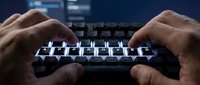 Man typing on mechanical keyboard with illuminated keys in dark environment, suitable for gaming, technology, and productivity content.