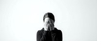 Young woman covering face with hands expressing stress, depression or emotional pain on white background for mental health awareness campaigns.
