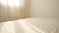 Empty wooden table surface with soft sunlight streaming through window creating warm atmospheric lighting for product display and food photography.