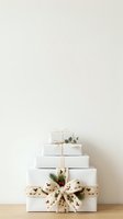 Stacked white gift boxes with natural twine bows and evergreen sprigs create a minimalist holiday display. Perfect for seasonal marketing, greeting cards, and festive design projects.