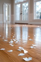 White paper confetti scattered on polished hardwood floor in bright interior room with large windows and natural light, creating romantic atmosphere for celebrations.