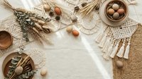 Rustic boho flat lay with dried wheat, macrame decor, wooden bowls and natural eggs on neutral textured background for organic lifestyle branding.