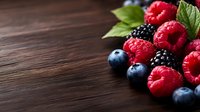 Fresh mixed berries raspberries blueberries blackberries with mint leaves on rustic wooden table background for healthy eating and organic food concepts.