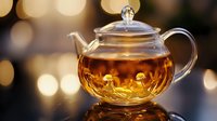 Glass teapot with golden tea and warm bokeh lights creating cozy atmosphere for relaxation and mindfulness moments.