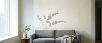 Modern living room with gray upholstered sofa, minimalist wall decal, wooden side table with vase, and natural light from window for home interior design.