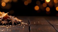 Festive winter spices and golden decorations on rustic wooden table with warm bokeh lights creating cozy holiday atmosphere. Macro food photography.