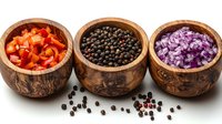 Fresh red bell peppers, black peppercorns and purple onions in decorative wooden bowls arranged in row on white background, culinary spices and ingredients.