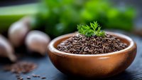 Organic caraway seeds in wooden bowl with fresh herbs on dark surface for culinary cooking and natural spice seasoning in kitchen food preparation.