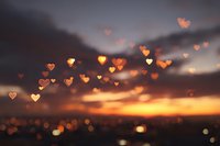 Romantic sunset sky with glowing heart-shaped bokeh lights creating dreamy atmosphere for love and Valentine's Day celebrations.