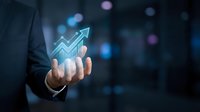 Businessman hand holding glowing upward arrow graph symbol representing financial growth, success, and rising profits in digital business analytics and investment strategy.