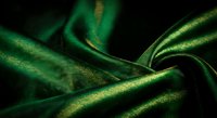 Luxurious emerald green silk fabric with smooth flowing texture and elegant drape, perfect for fashion design, textile backgrounds and premium material concepts.