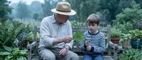 Grandfather and grandson bonding while gardening together on wooden bench surrounded by lush green plants and potted herbs in backyard garden setting.