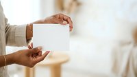 Close-up of hands holding blank white card for business messaging, greeting, or promotional content display.