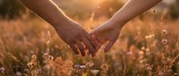 Two hands forming a heart shape over wildflowers in golden sunlight, symbolizing love, unity, and connection with nature for romantic and wellness designs.