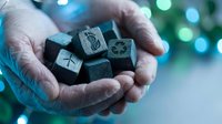 Person holding metal dice with symbols in cupped hands against blurred bokeh background with blue and green lights, suitable for gaming, fortune telling, and chance concept illustrations.