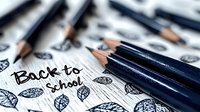 Sharp pencils arranged on paper with hand drawn back to school text and autumn leaf doodles. Educational supplies and creative sketching create nostalgic composition.