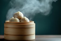 Steaming hot dumplings in traditional bamboo steamer basket against dark green background, with rising vapor creating atmospheric food photography mood.