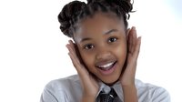 Young African American girl with braided hairstyle expressing surprise and joy with hands on face against white background. Great for education or emotional concepts.
