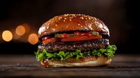 Juicy beef burger with fresh lettuce, tomato, and sesame seed bun photographed on dark wooden surface with soft bokeh lights in background creating appetizing mood.
