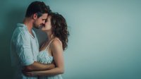 Romantic couple embracing intimately with foreheads touching in tender moment against soft teal background for love and relationship concepts.