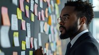 African American businessman in glasses and suit analyzing sticky notes on wall during strategic planning session in modern office space.
