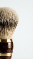 Luxury shaving brush with natural bristles and wooden handle featuring brass accents, isolated on white background for grooming and men's personal care product design.
