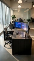 Modern office workspace with curved monitor displaying financial data analytics dashboard in contemporary business environment with natural lighting.