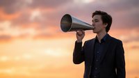 Young businessman speaking through megaphone against dramatic sunset sky for leadership and communication concepts in corporate marketing campaigns.