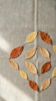 Autumn leaves arranged in geometric pattern on natural linen fabric background for seasonal crafts and home decor projects.