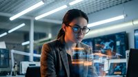 Professional businesswoman analyzing holographic data visualization in modern office environment with digital interface technology.