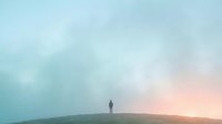Silhouette of solitary figure standing on hilltop at sunrise or sunset with misty atmospheric landscape, conveying contemplation, solitude, and new beginnings for editorial and motivational use.